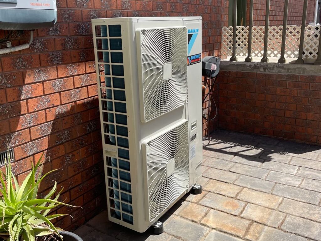 Daikin outdoor condenser unit installed beside a brick home for residential heating and cooling