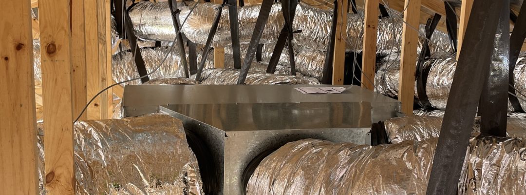 Indoor ducted heating and cooling unit connected to insulated ductwork in roof space